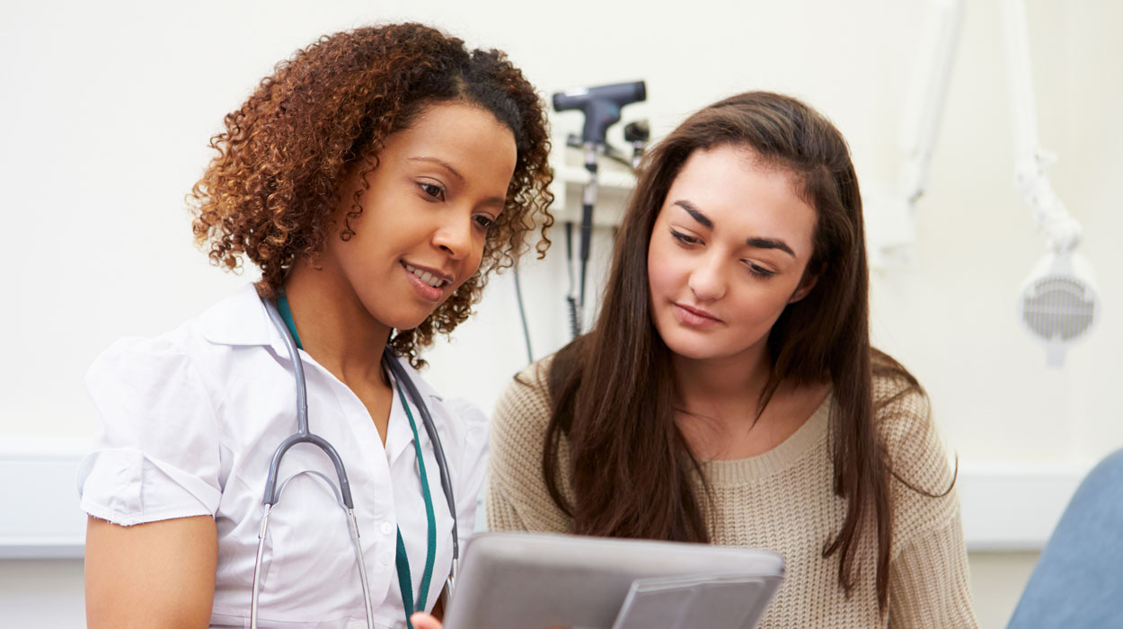 A medical professional utilizes their spa management software with a client.