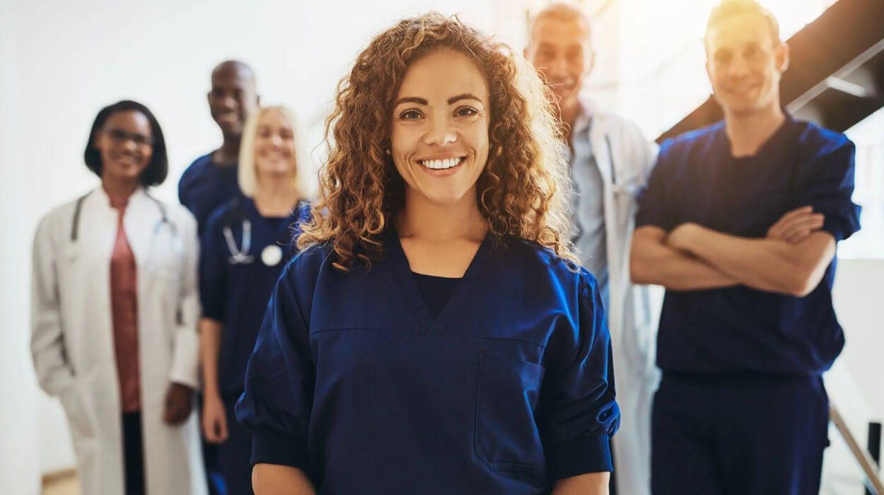 Smiling young female doctor standing in front of a team of medical aesthetics professionals.