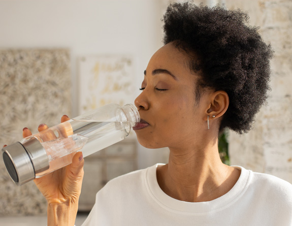 Mother enjoying a bottle of water offered as a complimentary refreshment at her medical spa appointment.