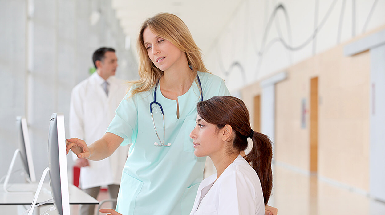 Nurse working with employee in front of computer