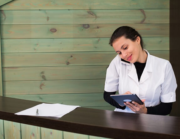 Spa receptionist talking on a phone while using a tablet