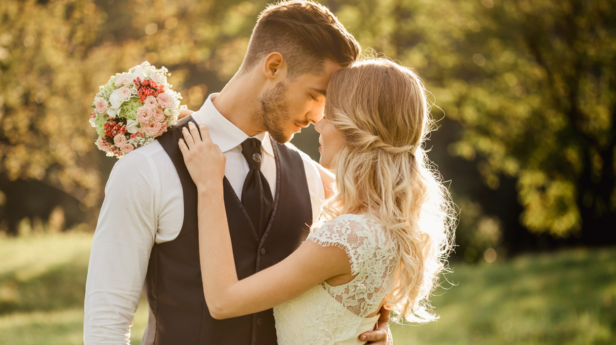 A couple at their wedding embracing and posing for a photo.
