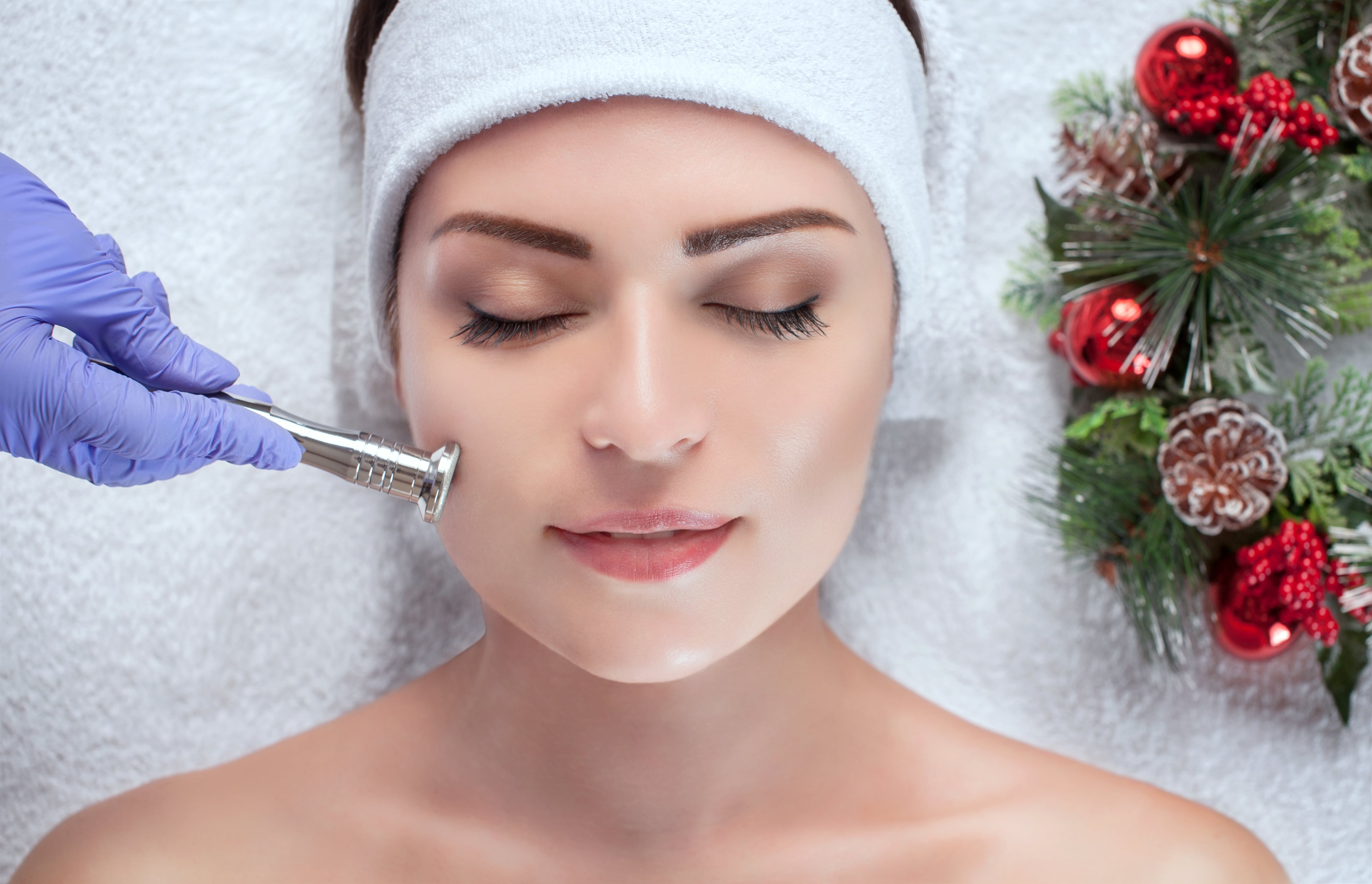 Woman receives aesthetic procedure while lying by holiday wreath