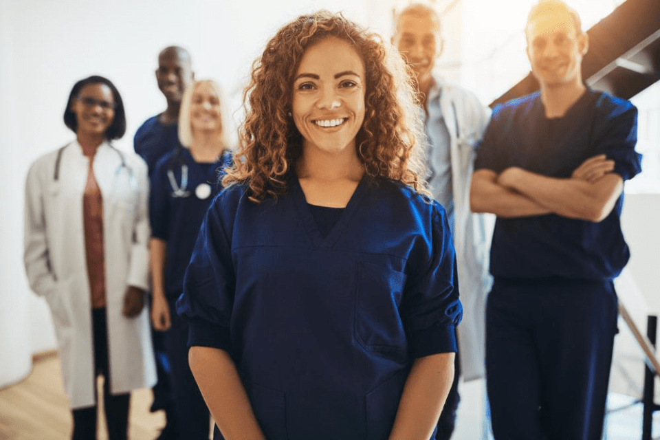 Smiling young female doctor standing in front of a team of medical aesthetics professionals.