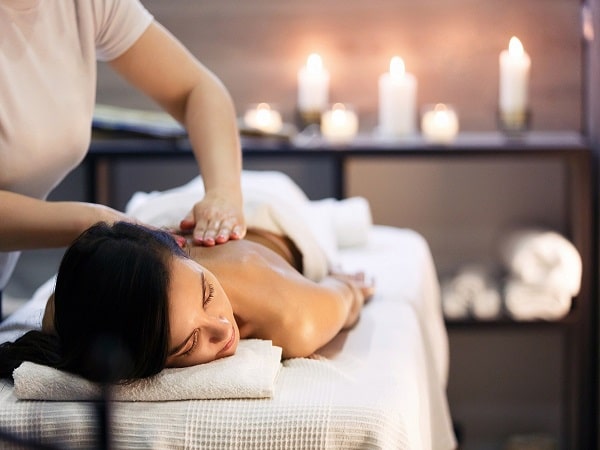 A person receiving a massage in a candle lit room